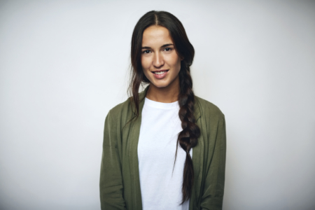 Portrait of businesswoman with braided hair. Confident female professional is wearing jacket. She is smiling over white background.
